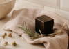 Panetto scuro di balsamo e maschera 43 Grani Ethical Grace su tessuto di lino, con rosmarino e fiori di camomilla essiccati